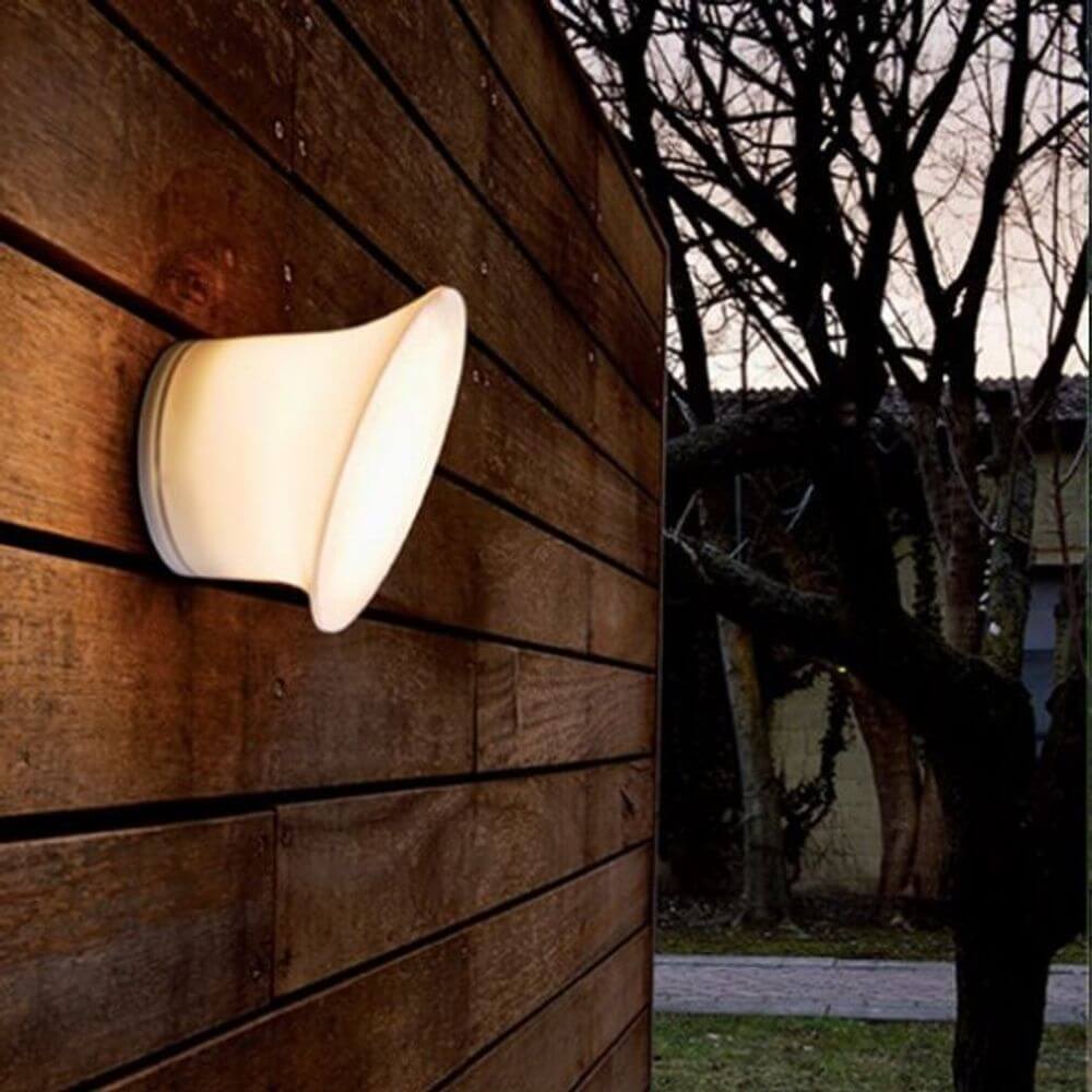 Luceplan LED Außen-Wandlampe Ecran IP65 an einer Holzwand, strahlt sanftes warmes Licht aus.