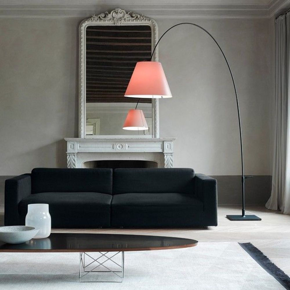 Luceplan Lady Costanza Bogenlampe mit Dimmer, elegante Wohnzimmerbeleuchtung über schwarzem Sofa.