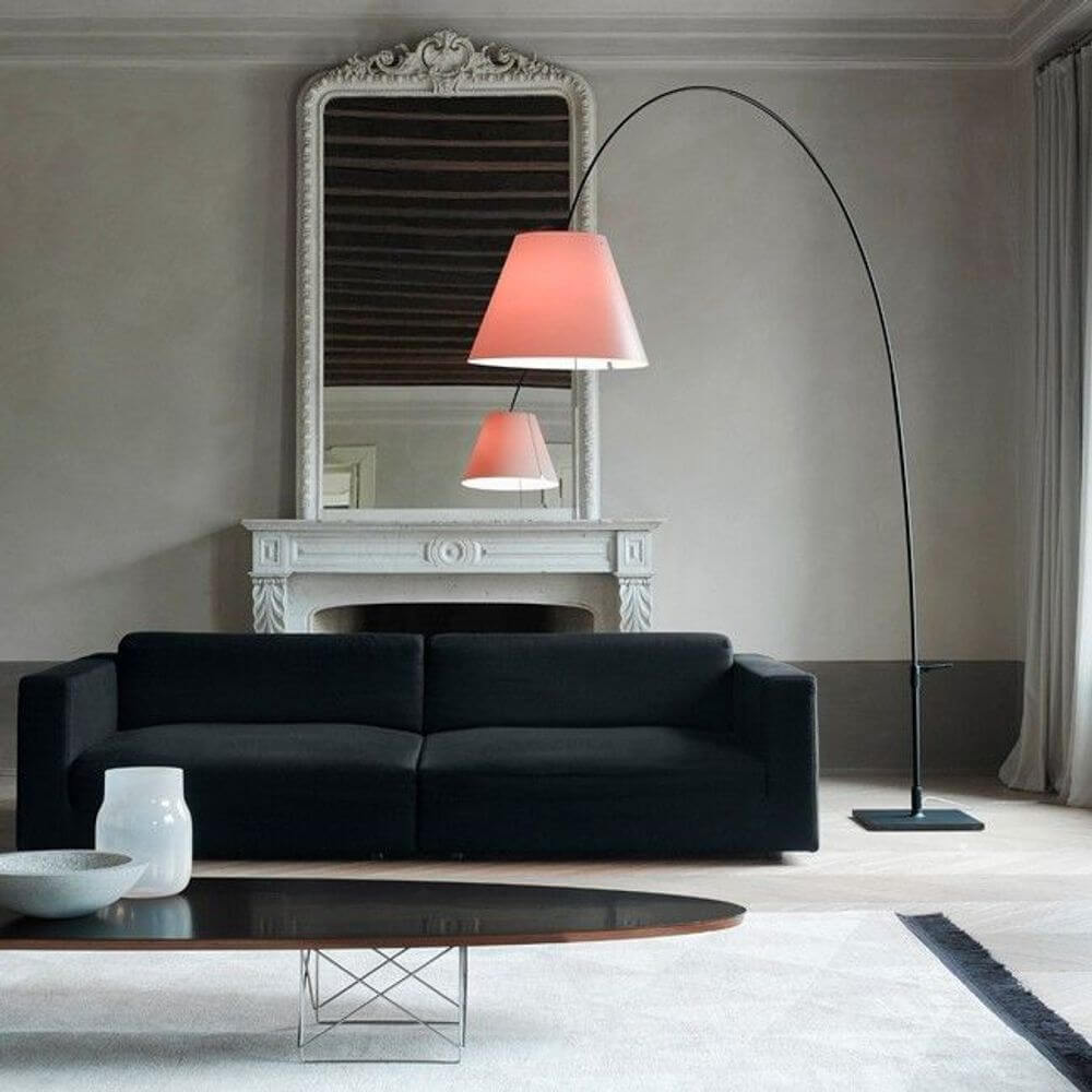 Luceplan Lady Costanza Bogenlampe mit Dimmer in elegantem Interieur neben schwarzem Sofa und großem Spiegel.