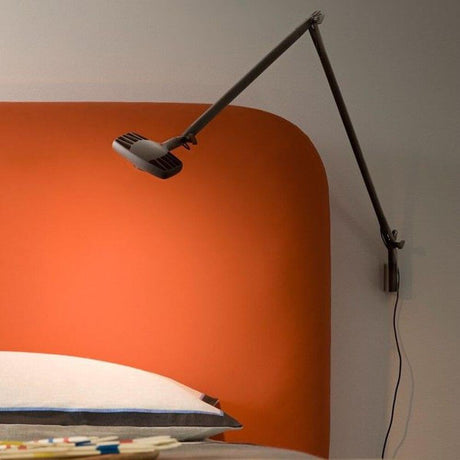 Luceplan Otto Watt Wandhalterung an einer orangefarbenen Wand über einem Bett.