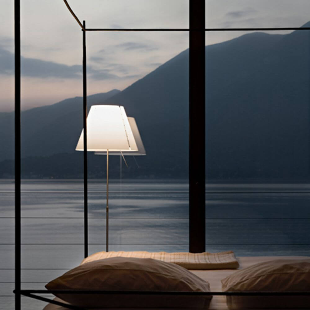 Luceplan Stehlampe Costanza mit Sensor-Dimmer D13 c in eleganter Umgebung mit Blick auf den See.