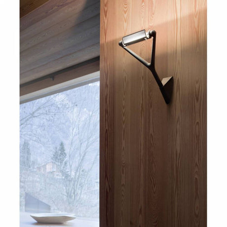 Luceplan væglampe Lola lyseffekt kan drejes på en trævæg, viser moderne design og belysningsaccent.