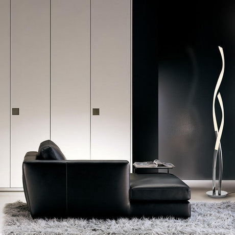 Lampadaire Armonia LED à côté d’un canapé noir moderne dans un salon élégant.