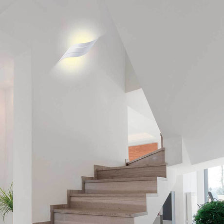 Tahiti LED-Wandleuchte geschwungen Weiß-Matt an einer Wand über einer Treppe.