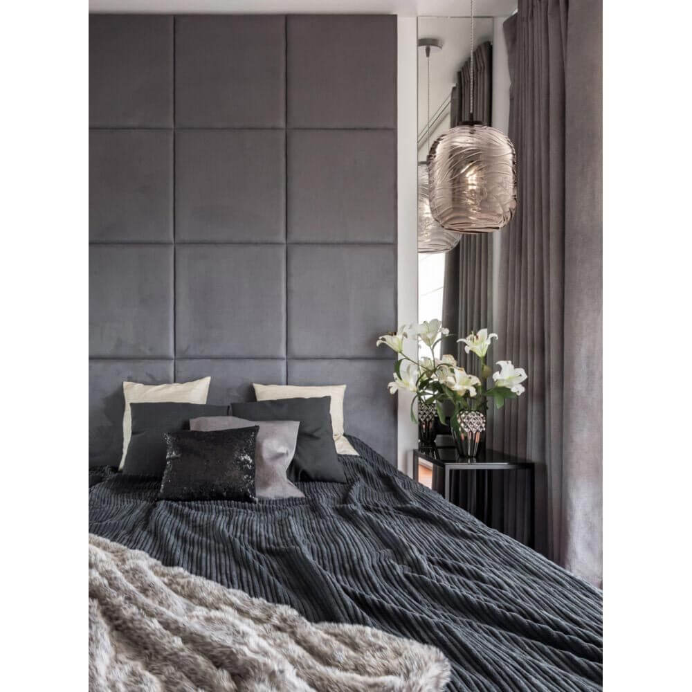 Dunas Pendelleuchte Small über einem modernen Bett mit grauen Wänden und stilvollen Kissen.