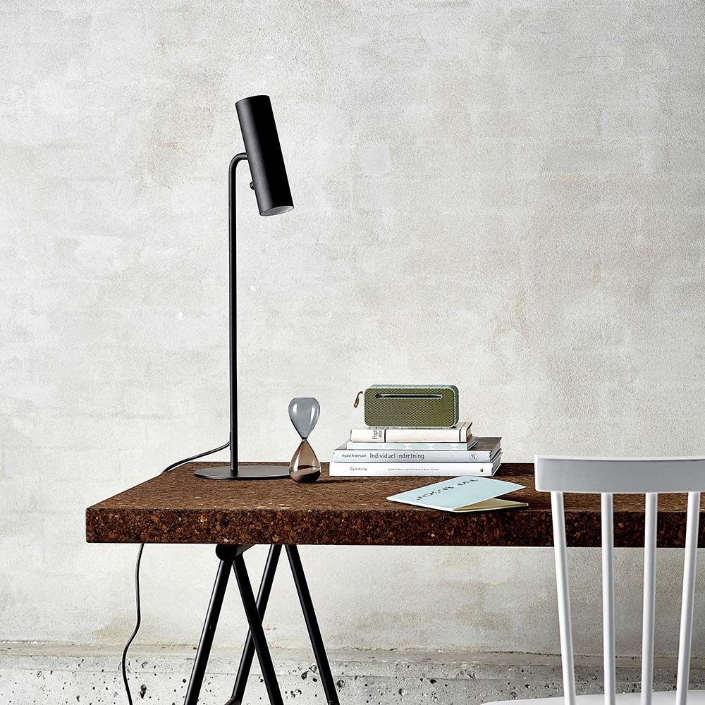 Mib 6 Tischleuchte Schwarz auf einem modernen Tisch mit Büchern und Dekoration.