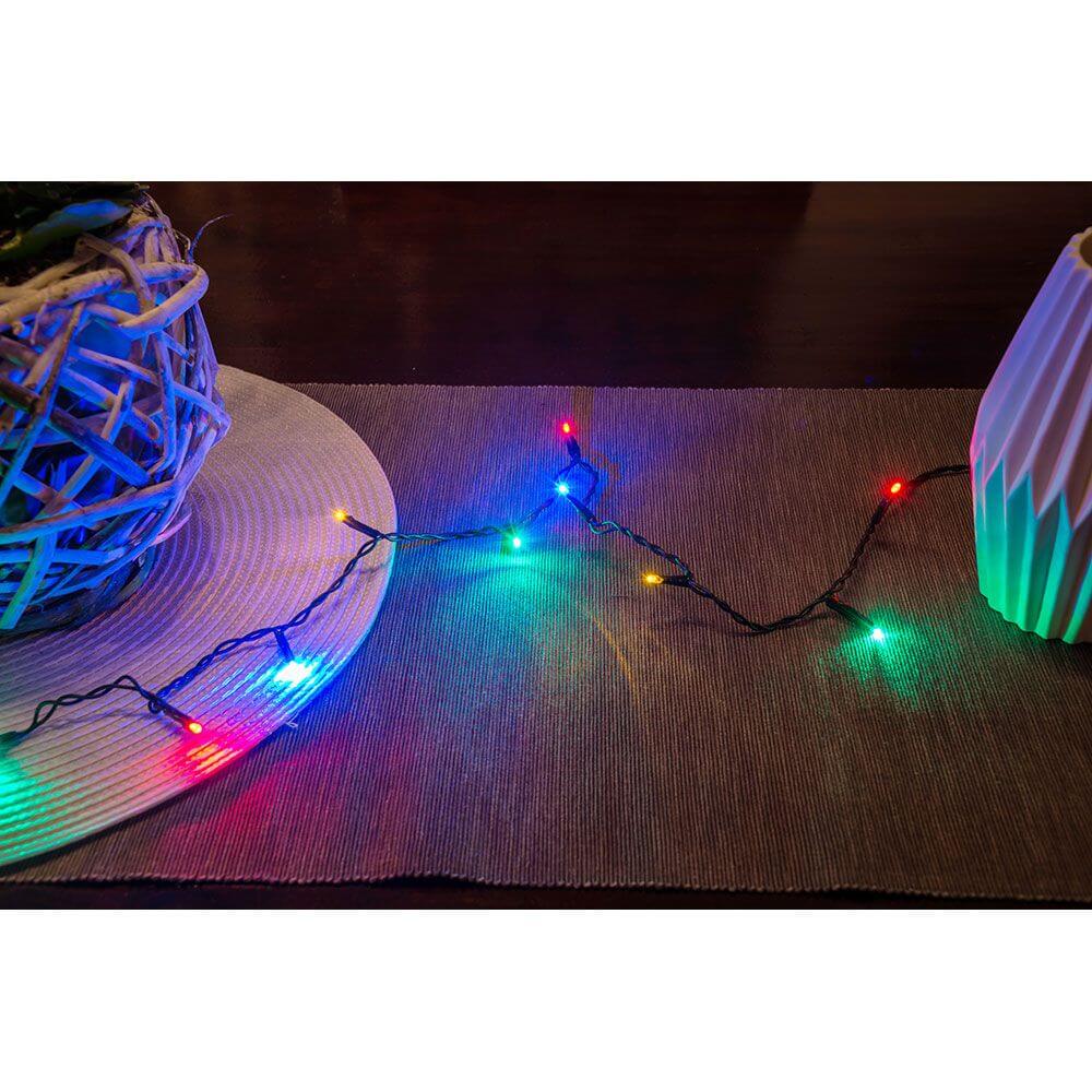 6m Micro LED Lichterkette mit 100 bunten Dioden leuchtet auf einem Tisch neben einer Dekovase.