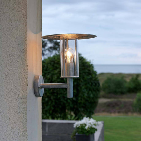 Mode utendørs vegglampe i galvanisert stål, klart polykarbonatglass installert på en vegg.