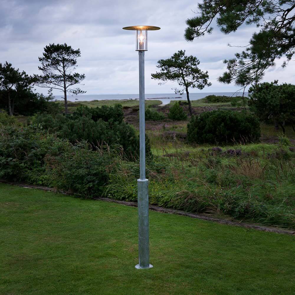 Mode Mastleuchte 220cm galvanisierter Stahl, klares Polycarbonat Glas im Garten bei Dämmerung.