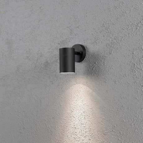 Modena outdoor wall light black, clear glass, reflector on a wall with a soft glow.