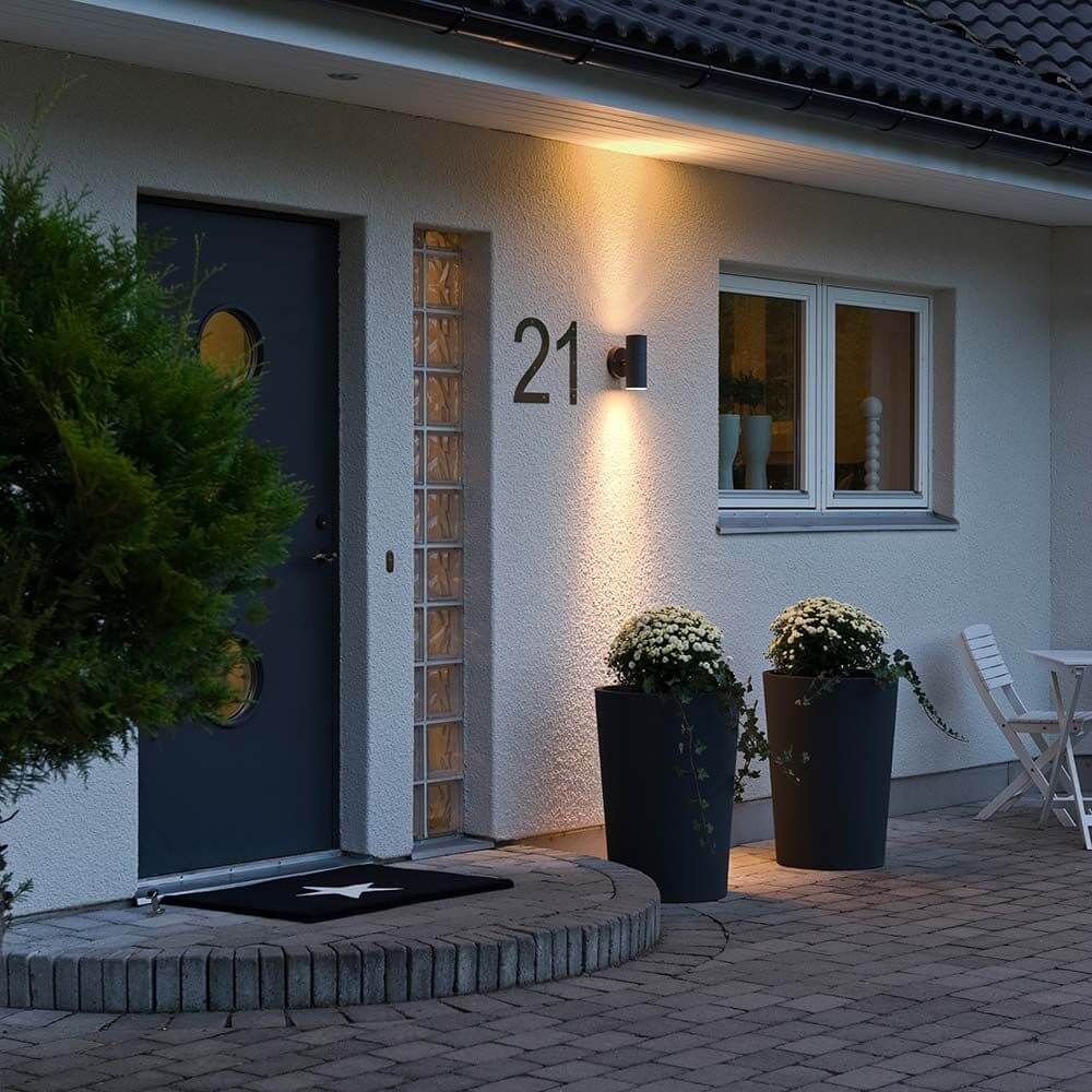 Modena Außen-Wandleuchte mit doppeltem Lichtkegel Schwarz, klares Glas, Reflektor an einer Hauswand bei Nacht.