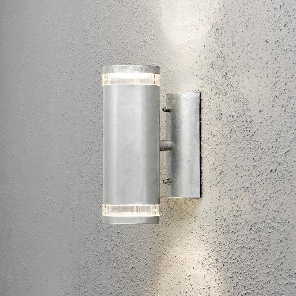 Außen-Wandlampe Modena mit Doppel-Lichtkegel an einer grauen Wand installiert.