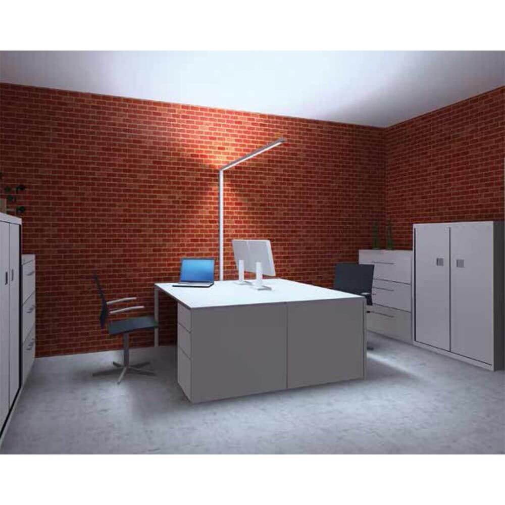 Moderne Büroumgebung mit Lens Stehleuchte, Schreibtisch und ergonomischem Stuhl vor Backsteinwand.
