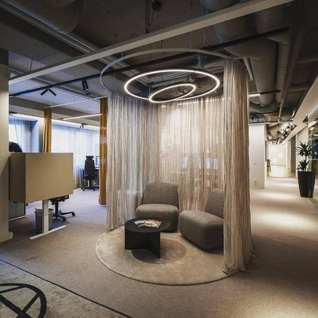 Rinq LED-ringlelys Ø 150 cm svart DALI-dimbar i et moderne kontor med hengende gardiner og sitteområde.