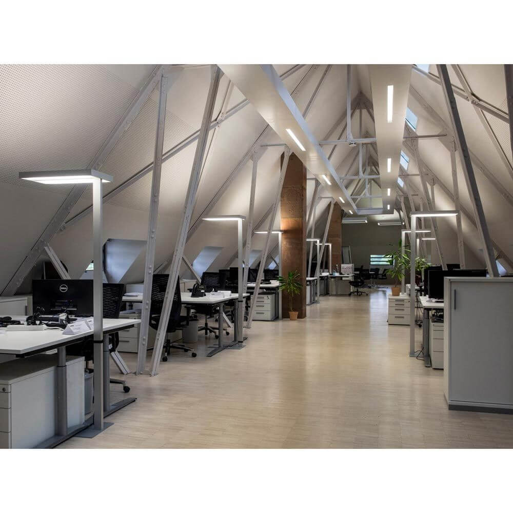 Helles Büro mit modernen Stehleuchten und stilvollen Arbeitsplätzen unter einem Dach mit Holzträgern.