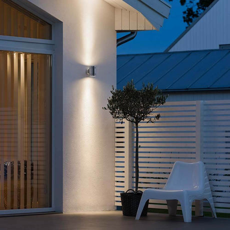 Monza LED outdoor wall light with double light beam on an exterior wall, illuminating the space.