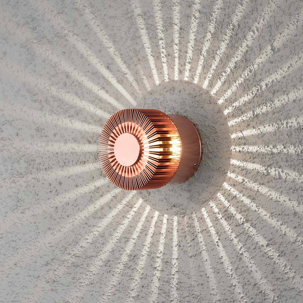 Monza LED Effekt Außen-Wandleuchte Kupferfarben an einer Wand mit Strahlenmuster.