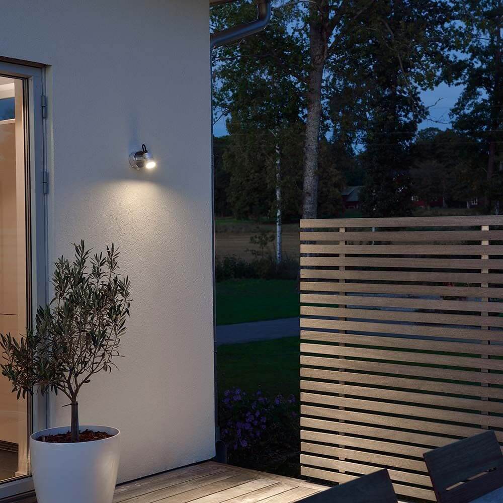 Monza LED Außen-Wandspot mit Bewegungsmelder Alu leuchtet eine moderne Terrasse bei Nacht.