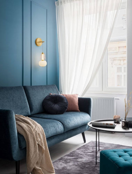 Modern interior design with Movil wall light 3000K Gold above a blue sofa in a stylish living room.