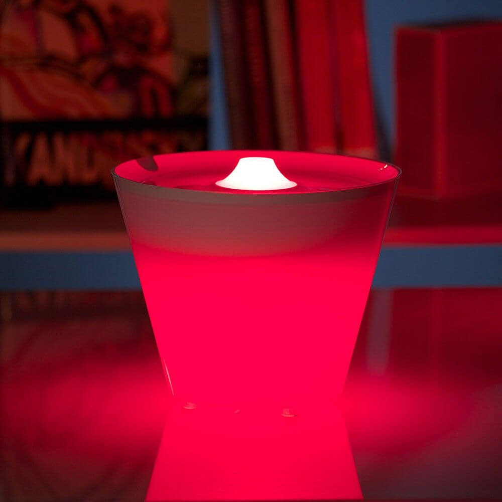 Rotaliana Multipot+ table lamp cable container + charging station white glowing red on a table.