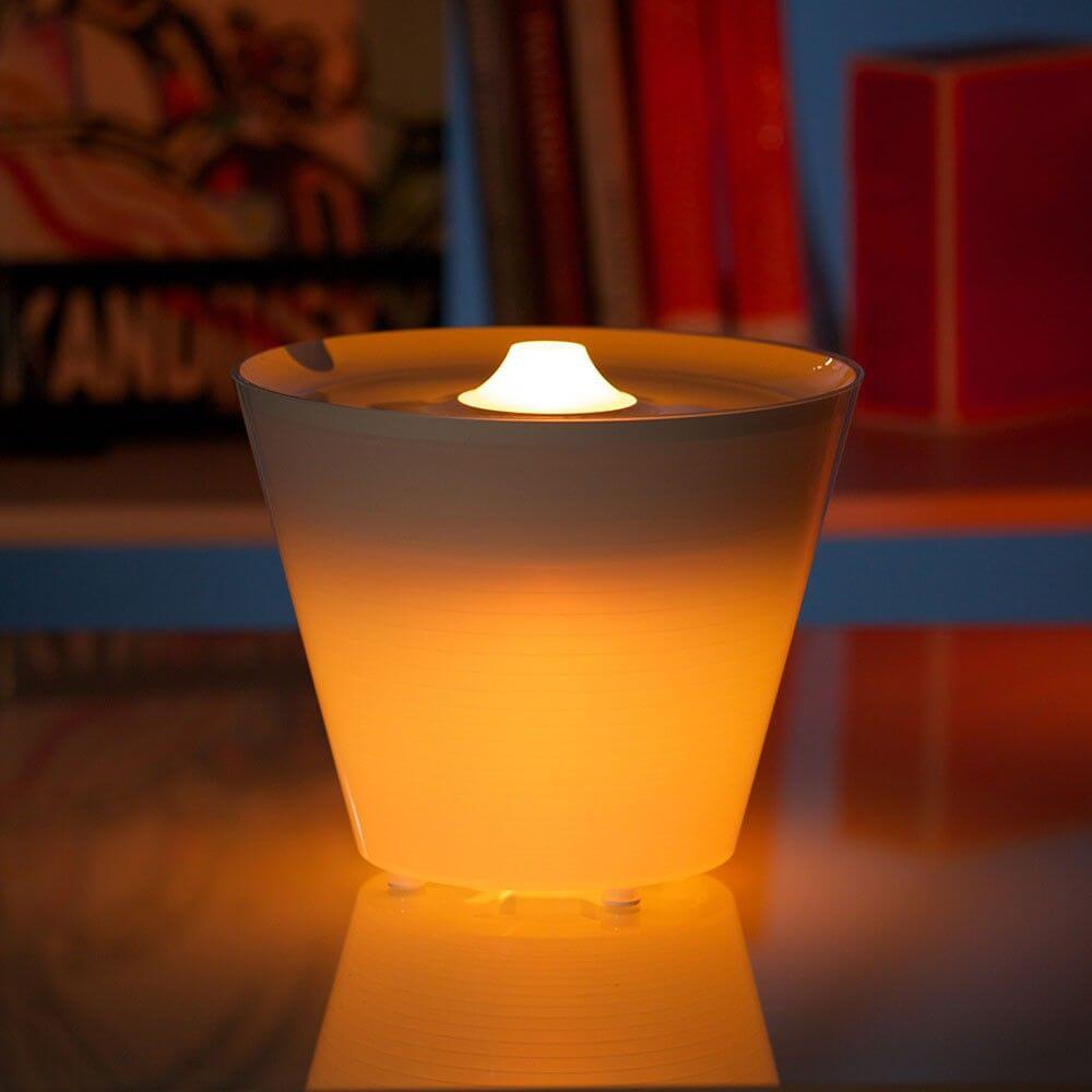 Rotaliana Multipot+ table lamp cable container + charging station white on a table with warm light.