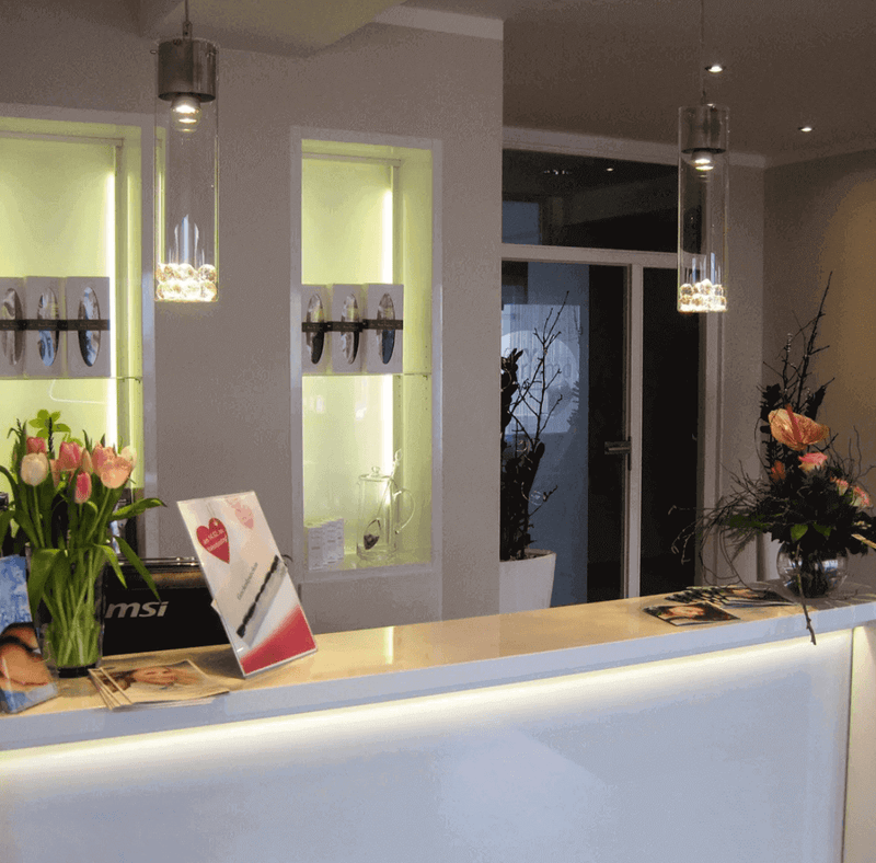 Moderne Empfangstheke mit Blumenarrangements und stilvollem Beleuchtungskonzept im Raum.