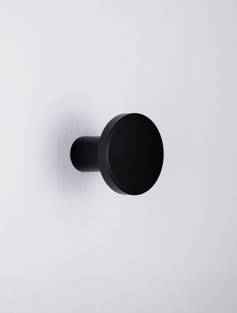 Nano Wandleuchte 3000K Schwarz an weißer Wand, kompaktes rundes Design, matte schwarze Oberfläche