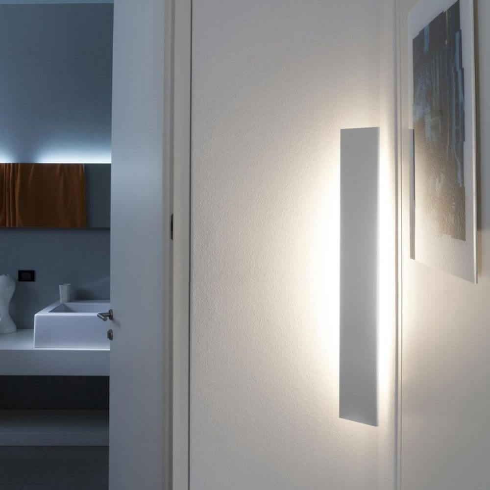 Nemo Angolo Mezzo LED Ecklampe 100cm an einer Wand installiert, indirektes Licht in einem modernen Raum.