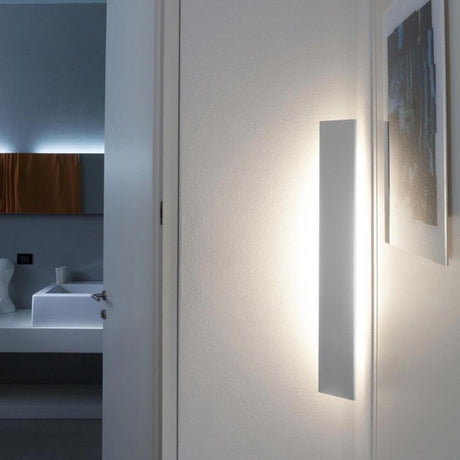 Nemo Angolo Mezzo LED lampe d’angle 100 cm installée sur un mur, lumière indirecte dans un espace moderne.