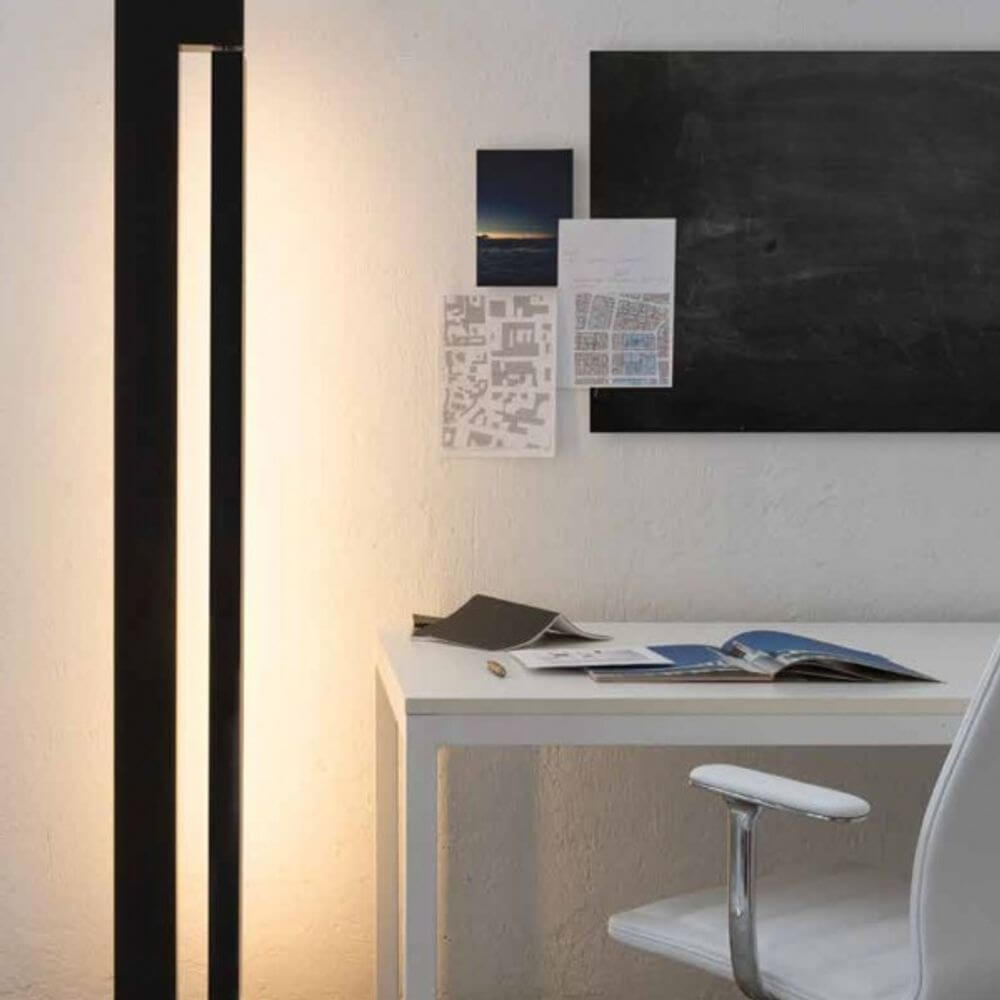 Nemo Ara LED Stehlampe drehbar im modernen Büro mit Schreibtisch und schwarzen Wandflächen.