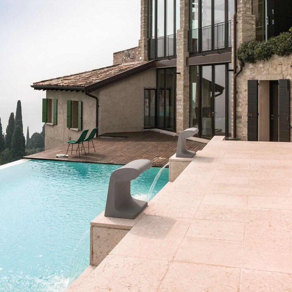 Nemo Borne Béton Petite Outdoor LED Tischlampe IP44 am Pool mit modernem Haus im Hintergrund.