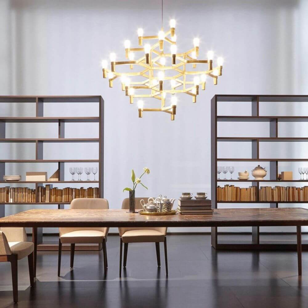 Nemo Crown Magnum Kronleuchter in modernem Esszimmer, goldene Leuchte über Holztisch und Regalen.