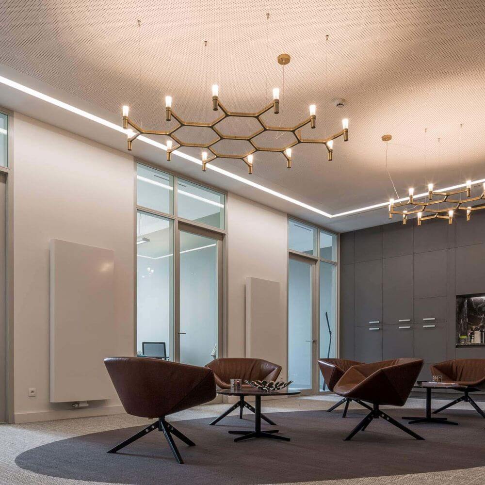 Moderne Büroeinrichtung mit Nemo Crown Plana Hängeleuchte und stilvollen Sesseln in einem hellen Raum.
