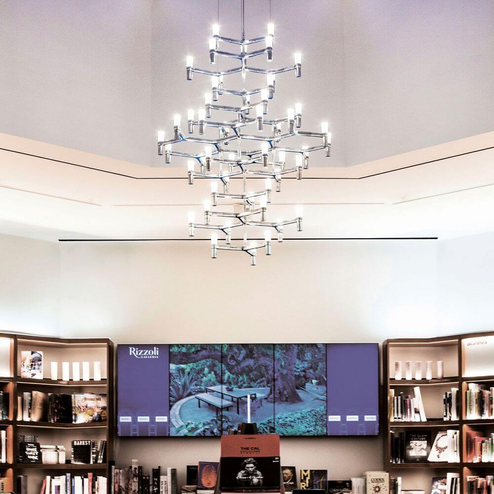 Nemo Crown Summa Hängelampe 48-flg. 157cm in einer modernen Buchhandlung mit Bücherregalen.