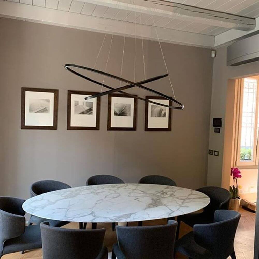 Nemo Ellisse Double Mega LED Hängeleuchte 186x95cm im Esszimmer über runder Marmor-Tisch mit stilvollen Stühlen.