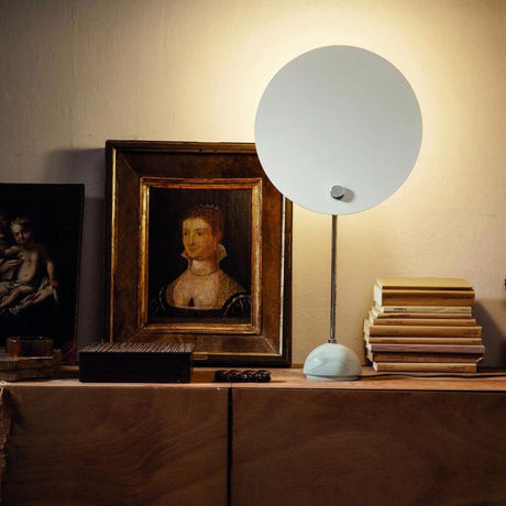 Nemo Kuta Tischlampe für indirektes Licht auf einem Tisch, beleuchtet Kunstwerke und Bücher.