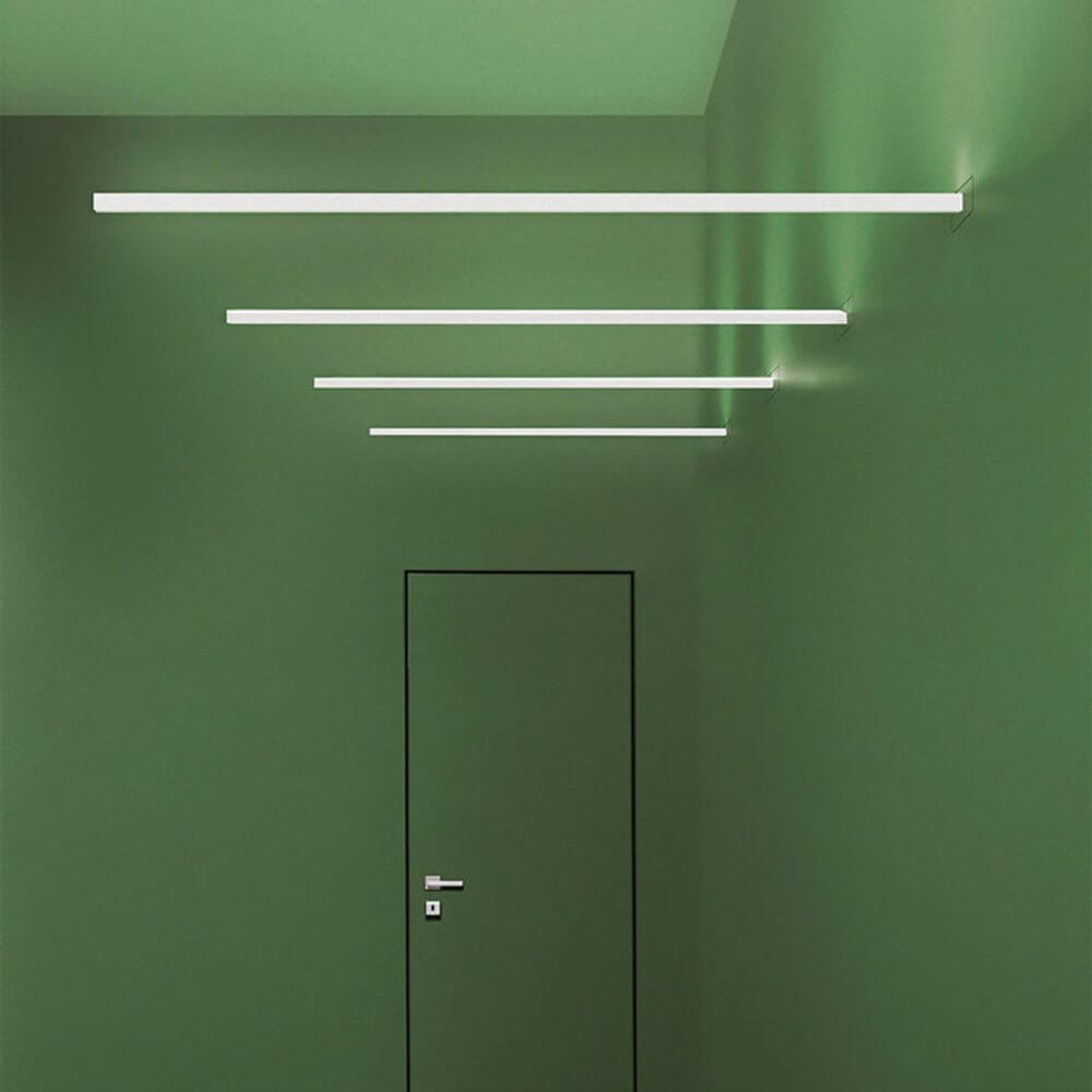 Moderne Wandleuchte in einem grünen Flur mit vier schmalen LED-Leisten, die direkt und indirekt beleuchten.