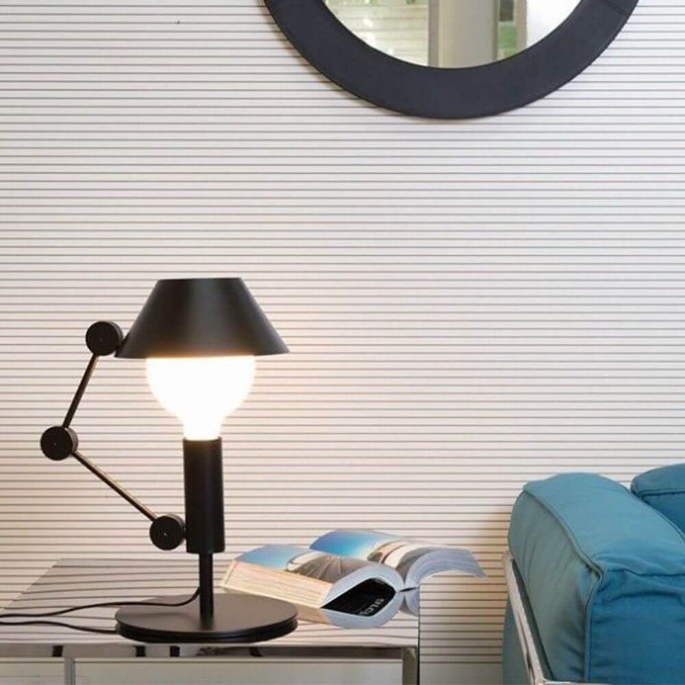 Nemo Mr. Light Tischlampe auf einem Tisch mit geöffnetem Buch und einem Spiegel im Hintergrund.