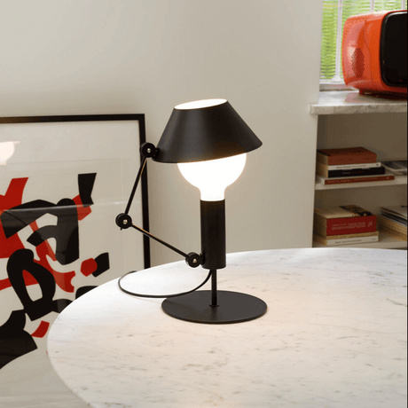 Nemo Mr. Light Tischlampe auf einem Tisch, mit beweglichem Arm und matt schwarzem Metall für diffuses Licht.