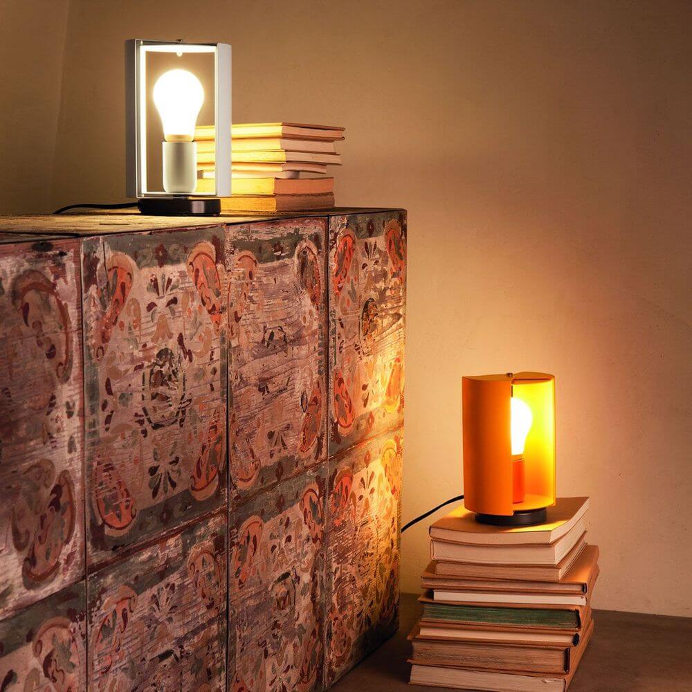 Nemo Pivotante À Poser Tischlampe drehbar auf einem dekorativen Regal mit Bücherstapeln.