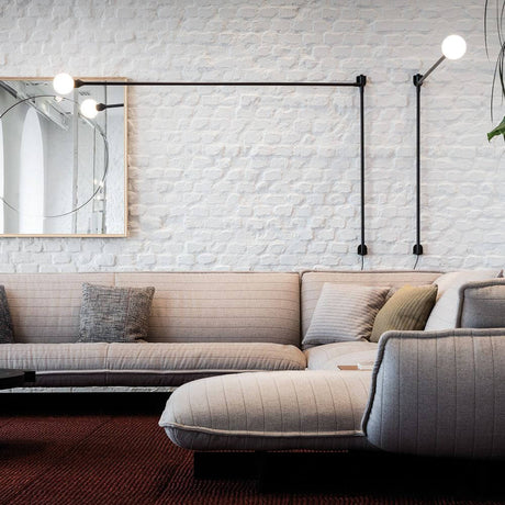 Nemo Potence Pivotante wall lamp 200cm on a wall above a modern sofa in a stylish living room.