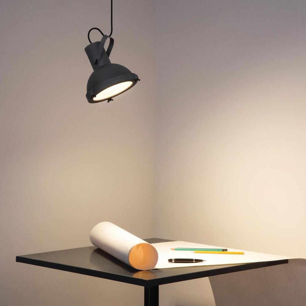 Nemo Projecteur 165 Hängeleuchte verstellbar über einem Tisch mit Skizzenrolle und Stiften.