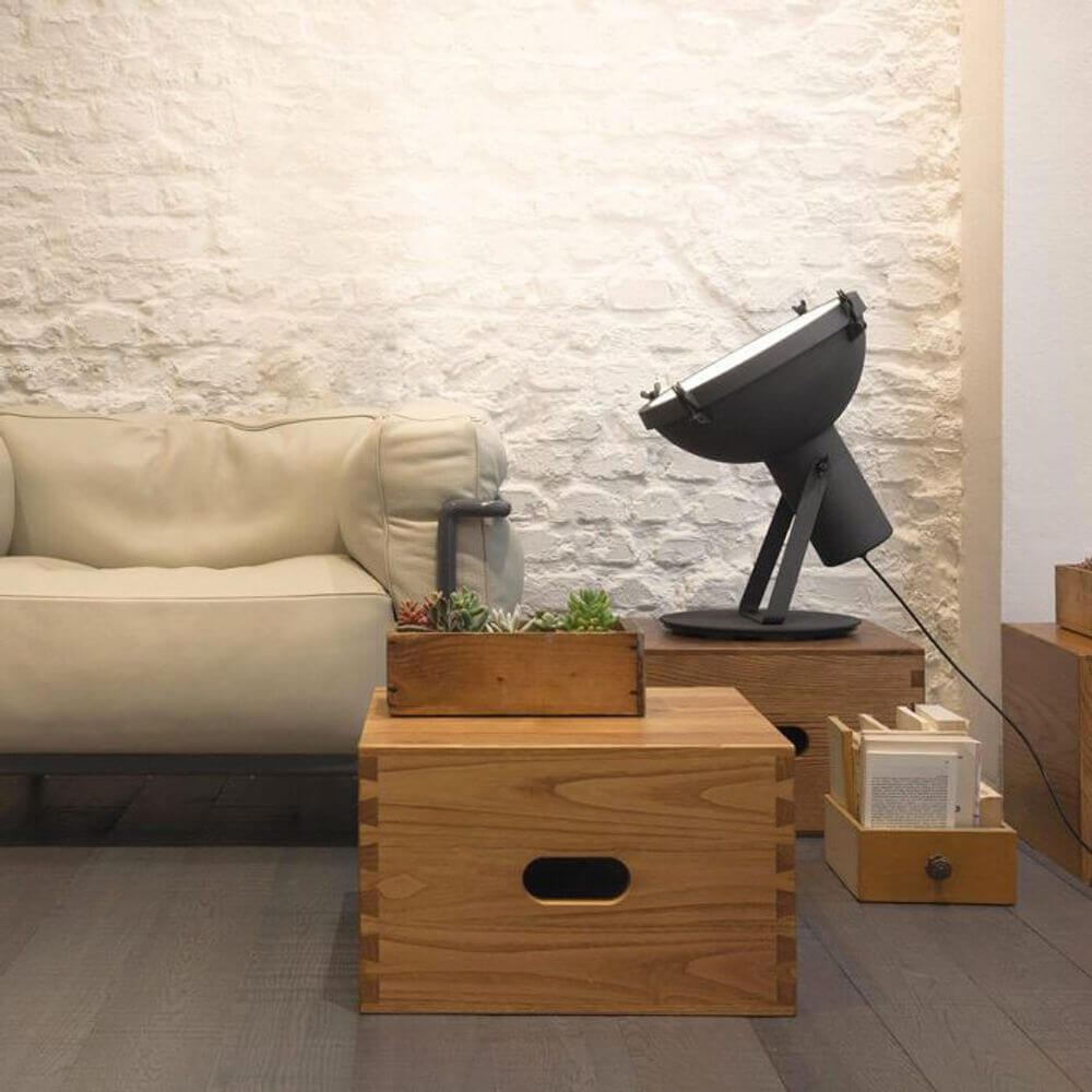 Nemo Projecteur 365 Stehlampe neben einer gemütlichen Couch und Holzkisten in modernem Raumdesign.