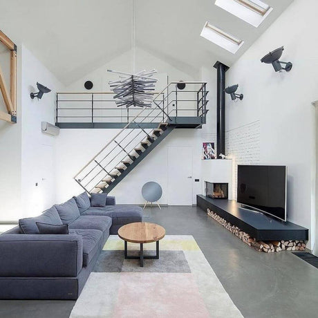 Elegant living room with Nemo Projecteur 365 wall spotlight, modern staircase and stylish furniture.