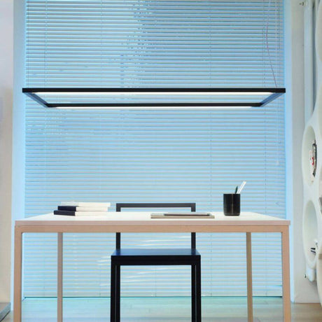 Suspension Nemo Spigolo Horizontal LED orientable au-dessus d’un bureau minimaliste avec surface en bois.