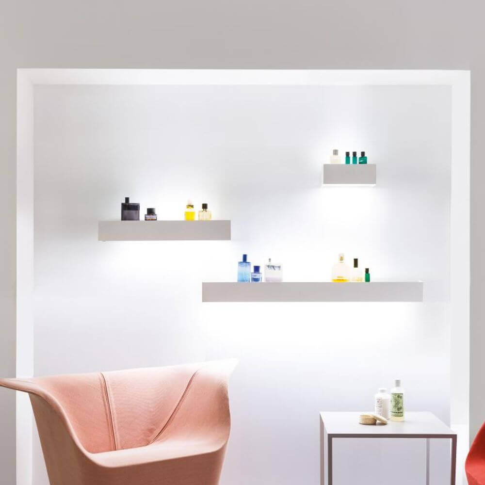 Nemo Viiva 30 LED Wandlampe Regal über weißen Regalen mit verschiedenen Pflegeprodukten.