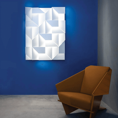 Nemo Wall Shadows Grand LED Wandlampe 120x90cm an blauer Wand neben einem modernen Sessel.