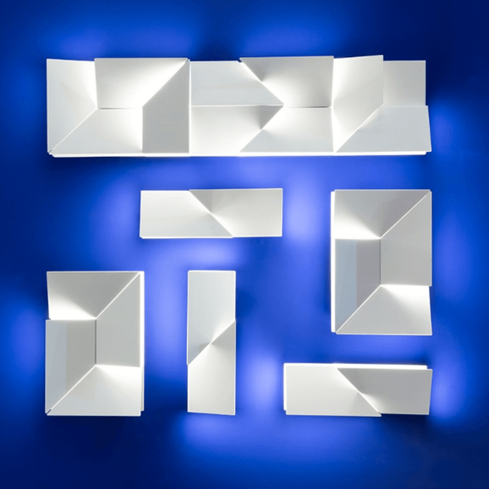 Nemo Wall Shadows Petit LED Wandlampe 15x45cm in einer künstlerischen Anordnung auf blauem Hintergrund.