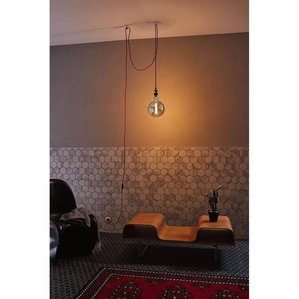Neordic Pendelleuchte Eldar inkl. Stecker Rot, Chrom in stylischem Retrolook über einem modernen Möbelstück.