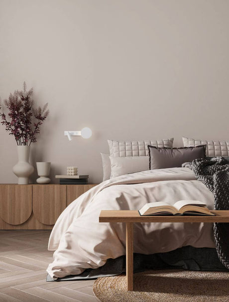 Cozy bedroom with Noima wall light 2-light 3000K white above a bed and a wooden table.